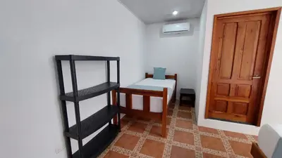 a small room with a bed and a wooden door at Hotel Casa THIREMA Tortuguero in Tortuguero