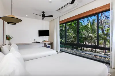 two beds in a bedroom with a large window at Luxury Beachfront Villa with private pool at Nantipa in Santa Teresa Beach