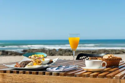 a table with food and a glass of orange juice at Luxury Beachfront Villa with private pool at Nantipa in Santa Teresa Beach