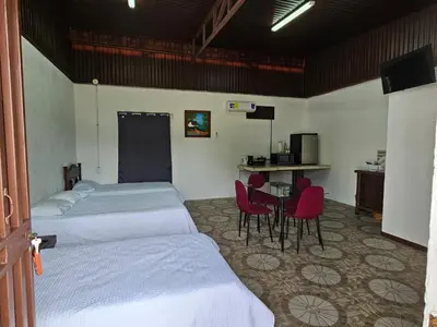 a bedroom with two beds and a table and chairs at Sleep&Go! Cabina Cuadruple en Siquirres Centro - and rafting tour! in Siquirres