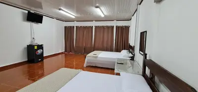 a hotel room with a bed and a television at Sleep&Go! Cabina Cuadruple en Siquirres Centro - and rafting tour! in Siquirres