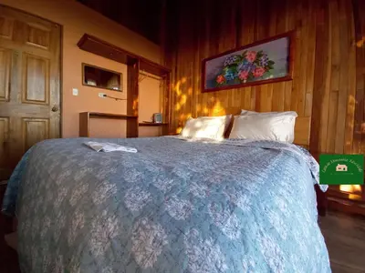 a bedroom with a large bed with a blue blanket at Casa de Montaña Tica Linda in Monteverde Costa Rica
