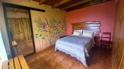 a bedroom with a bed and a painting on the wall at Casa de Montaña Tica Linda in Monteverde Costa Rica