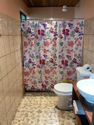 a bathroom with a shower curtain with a toilet at Casa de Montaña Tica Linda in Monteverde Costa Rica