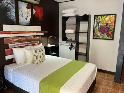 a bedroom with a bed with a green and white blanket at Sunrise House in Quepos