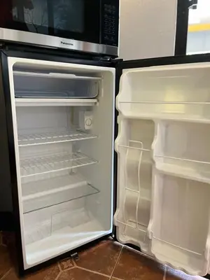 an empty refrigerator with its door open and a microwave at Sunrise House in Quepos