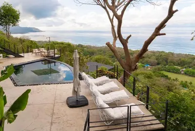 a pool with lounge chairs and a view of the ocean at Seataya Villas in Santa Teresa Beach