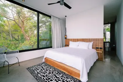 a bedroom with a bed and a large window at Seataya Villas in Santa Teresa Beach