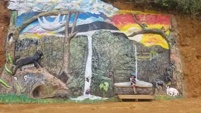 a mural on a wall with a child sitting on a bench next to a waterfall at Escapadita al Bosque in San Isidro