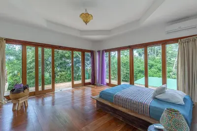 a bedroom with a bed and a bunch of windows at Villa Carlotta in Respingue