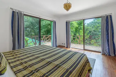 a bedroom with a bed and large windows at Villa Carlotta in Respingue