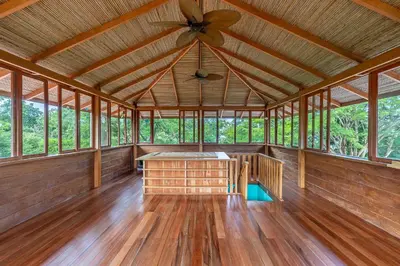 a large room with a ceiling fan and wood floors at Villa Carlotta in Respingue