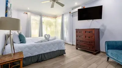 a bedroom with a bed and a flat screen tv at Elegant Condo with Brand-New Fixtures, Shaded Tropical Terrace, and Secluded Beach Access in Playa Flamingo