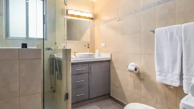 a bathroom with a sink and a shower with a mirror at Elegant Condo with Brand-New Fixtures, Shaded Tropical Terrace, and Secluded Beach Access in Playa Flamingo