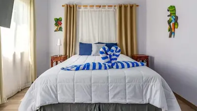 a bedroom with a large white bed with blue pillows at Elegant Condo with Brand-New Fixtures, Shaded Tropical Terrace, and Secluded Beach Access in Playa Flamingo