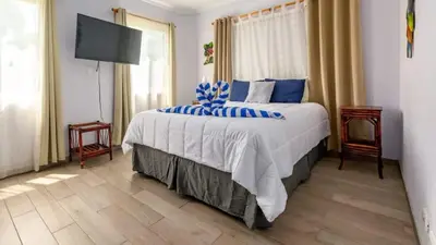 a bedroom with a large bed with blue pillows at Elegant Condo with Brand-New Fixtures, Shaded Tropical Terrace, and Secluded Beach Access in Playa Flamingo