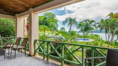 a porch with chairs and a view of the water at Elegant Condo with Brand-New Fixtures, Shaded Tropical Terrace, and Secluded Beach Access in Playa Flamingo