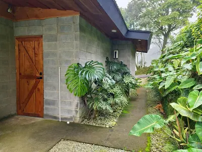 a house with a wooden door and some plants at Espectacular Cabaña Moderna de Montaña + Bosque Nuboso +Wifi in Zarcero