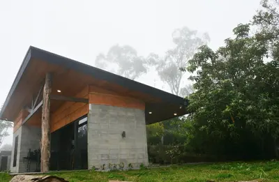 a house with a black roof and a tree at Espectacular Cabaña Moderna de Montaña + Bosque Nuboso +Wifi in Zarcero