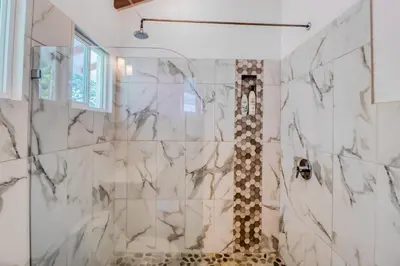 a bathroom with a shower with marble tiles at Lost Pools Bungalow in Uvita