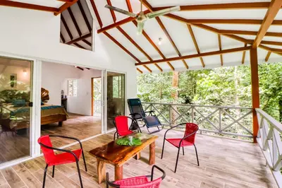 a living room with red chairs and a wooden table at Lost Pools Bungalow in Uvita