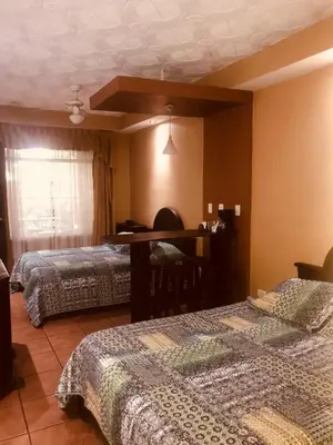 a room with two beds and a table in it at Melrost Airport Bed & Breakfast in Alajuela City