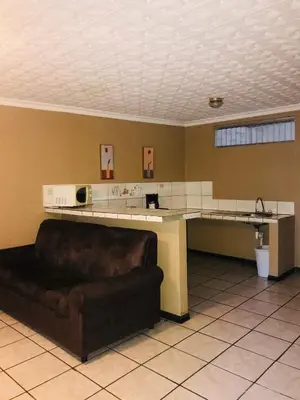a living room with a couch and a kitchen at Melrost Airport Bed & Breakfast in Alajuela City
