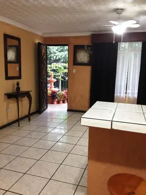 a room with a kitchen with a counter and a table at Melrost Airport Bed & Breakfast in Alajuela City