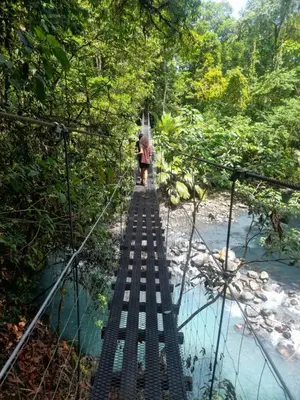 a person walking across a suspension bridge over a river at Onca Tours & Treehouses in San Rafael