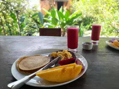 a plate of breakfast food with toast and fruit on a table at Onca Tours & Treehouses in San Rafael