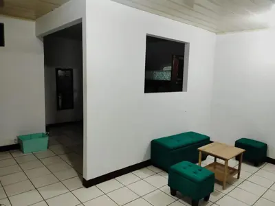 a room with two green chairs and a table at Departamentos Patricia in Alajuela City