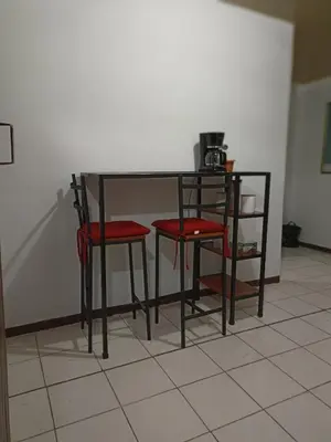 a black table with two red chairs next to a wall at Departamentos Patricia in Alajuela City