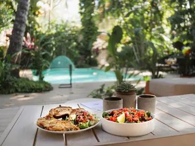 a table with a plate of food and a bowl of salad at Norte Nosara - Steps to Playa Guiones in Nosara