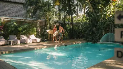 two people with surfboards standing next to a swimming pool at Norte Nosara - Steps to Playa Guiones in Nosara