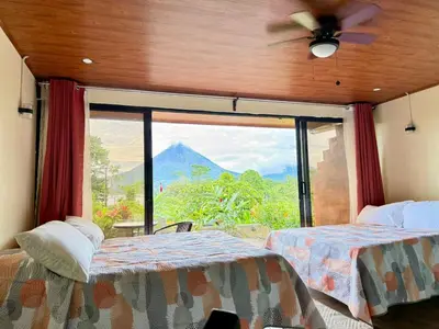 two beds in a room with a view of a mountain at Villas Paradise Arenal Volcano Lake View in El Castillo de La Fortuna