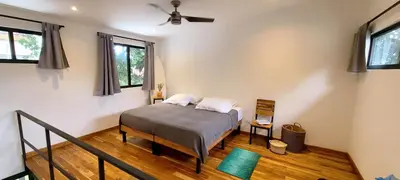 a bedroom with a bed with a fan and windows at El Hábita CASA MAR in Santa Teresa Beach