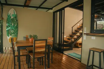 a dining room with a table and chairs and a surfboard at El Hábita CASA SELVA in Santa Teresa Beach