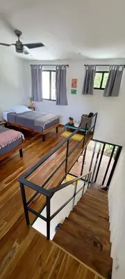 a living room with two beds and a staircase at El Hábita CASA SELVA in Santa Teresa Beach