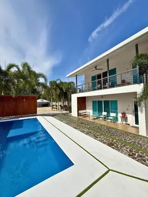 a villa with a swimming pool in front of a house at Nicoya Villas in Mal País