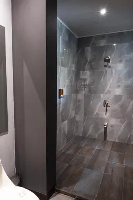 a bathroom with a shower with a stone wall at Hotel FAREMITI Uvita in Uvita