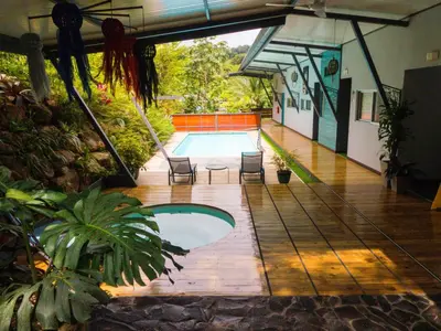 a swimming pool in the middle of a house with chairs at Hotel FAREMITI Uvita in Uvita