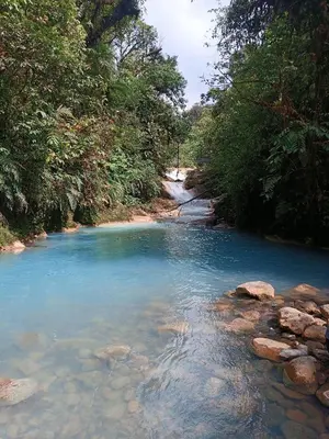 a river with blue water and rocks in a forest at Casa maar -Treetop tent in Río Cuarto