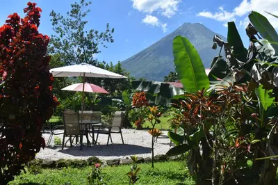 a patio with a table and chairs and a mountain at Hotel Roca Negra Del Arenal in Fortuna