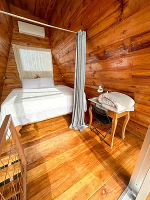a bedroom with a bed and a table in a log cabin at Tiny Villa Experience in Fortuna