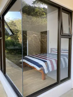 a glass room with a bed inside of it at Arte de Plumas birding lodge in Cartago