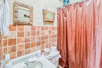 a bathroom with an orange shower curtain and a sink at Casita El Sastre in Paso Macho