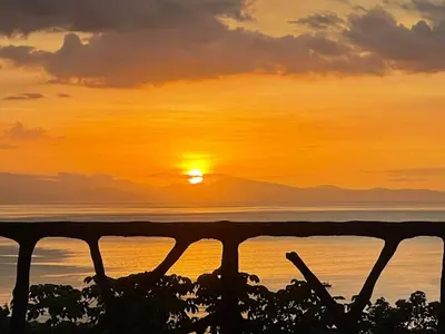 a sunset over the ocean viewed through a fence at Akua Suites Ocean View in Tarcoles