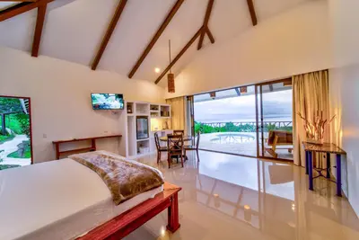 a bedroom with a bed and a living room at Akua Suites Ocean View in Tarcoles