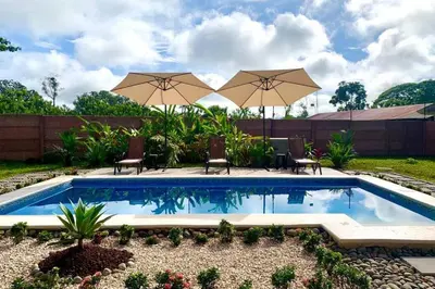 a swimming pool with two umbrellas and chairs at Villa Tropical La Fortuna in Fortuna