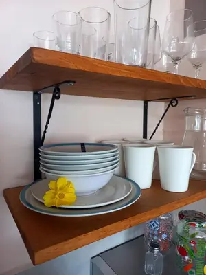 a shelf with plates and glasses and a yellow flower on it at Apartamentos y Studios Brisas del Mar Santa Teresa in Santa Teresa Beach
